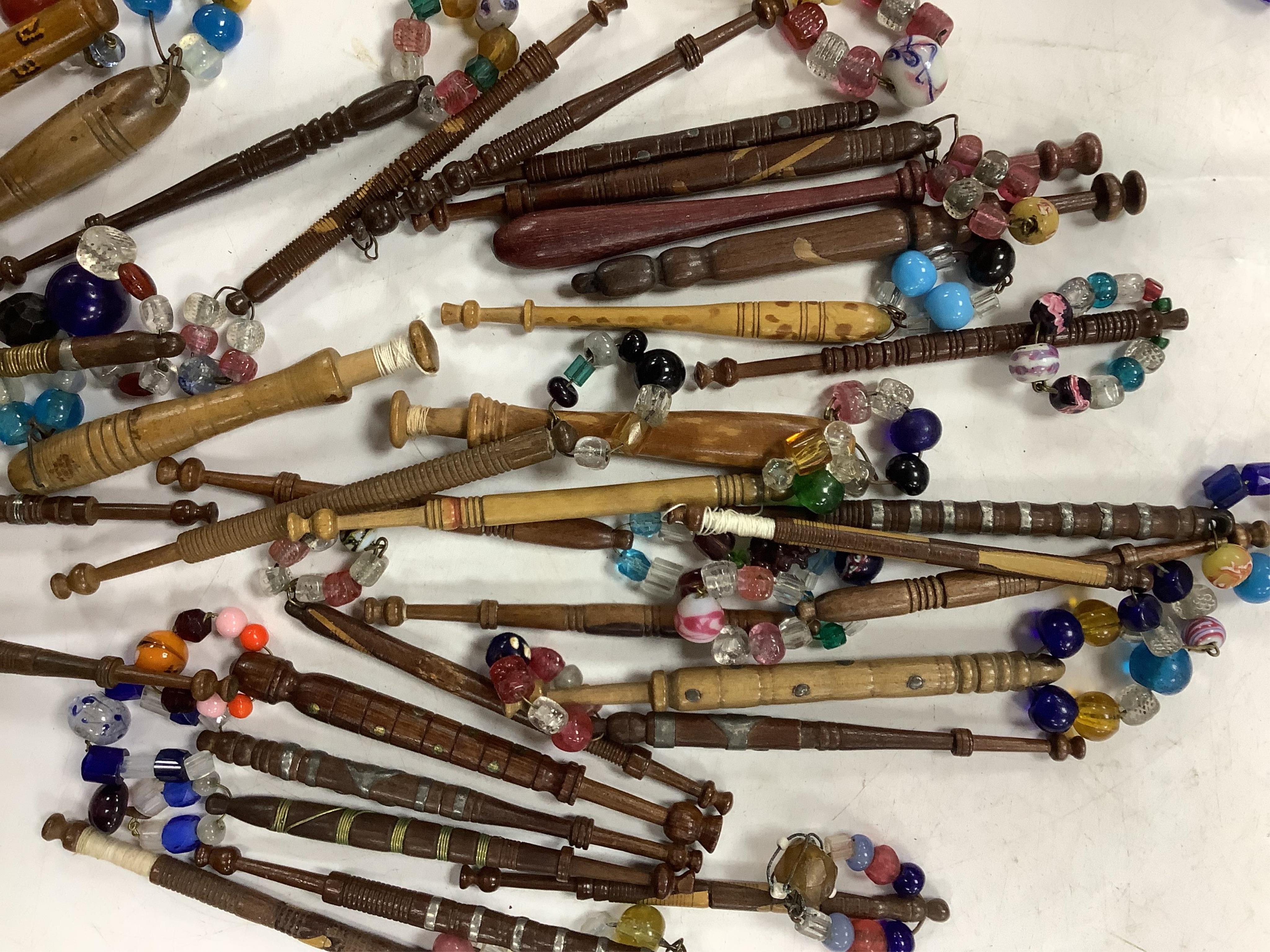 A collection of mostly 19th and 20th century ornate bone lace making bobbins, with coloured beaded ends, together with a similar smaller selection of wooden bobbins. Condition - good